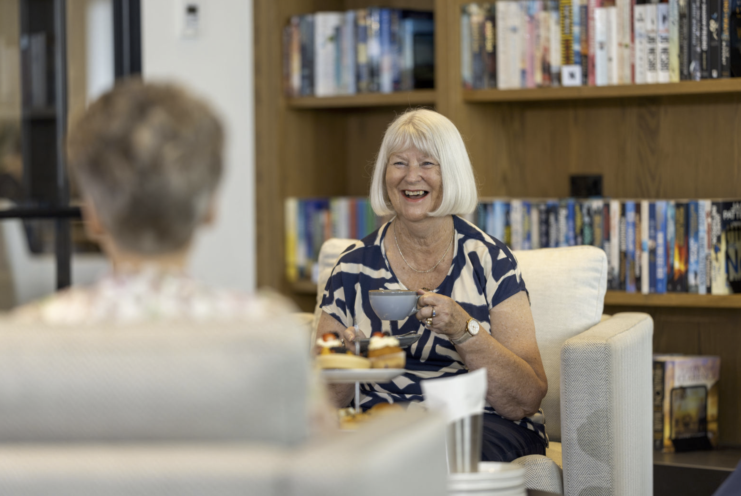 An elderly woman with white hair wearing a blue and white striped shirt, photographed during a corporate production